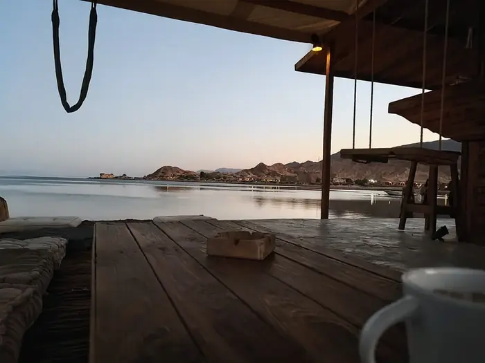 Twilight over the water seen from the cafe deck, with floor cushions and a wooden swing